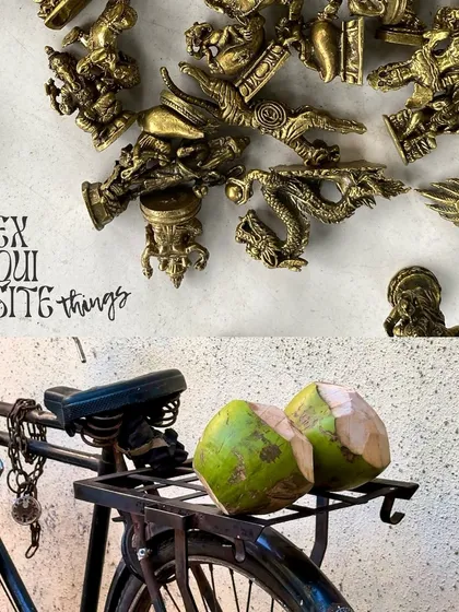 Exquisite things. A shot of two coconuts resting on the back of a bicycle, next to a display of small brass antiques.
