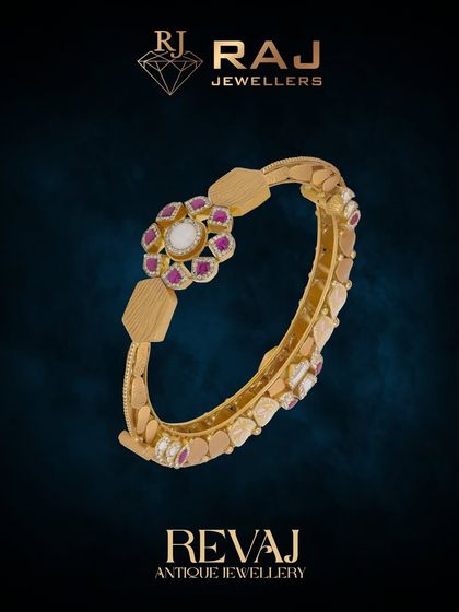 This elegant Revaj bangle features a central floral medallion set with a polki stone and rubies. The band itself has a unique, textured design, making it a beautiful statement of antique craftsmanship.