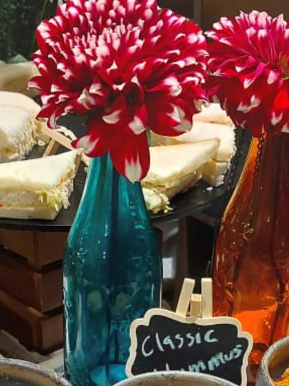 Colorful flower arrangements in recycled bottles add a pop of color and a touch of sustainable chic to our wine and cheese setups.