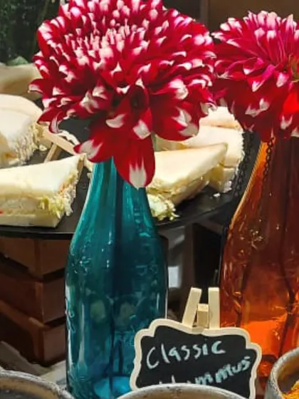 The vibrant floral arrangements in colorful bottles were a key part of the decor for this corporate wine and cheese event. They added a pop of color to the sophisticated spread of sandwiches and hummus.