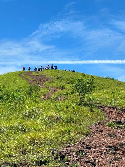 The trail leading up to the Kodachadri peak, with trekkers visible on the summit under a clear blue sky.