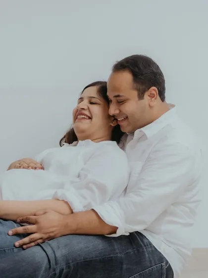 Pure, unscripted happiness. This candid photo captures the couple sharing a laugh, highlighting the easygoing and comfortable atmosphere of a lifestyle maternity session at home.