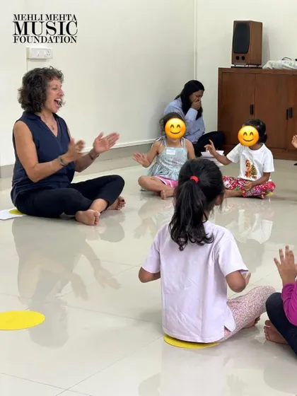 Our training is led by UK-based expert Naheed Shimala. This image captures a moment of joyful interaction in one of her sessions, demonstrating how she connects with young learners through expressive singing and hand gestures to teach musical concepts.