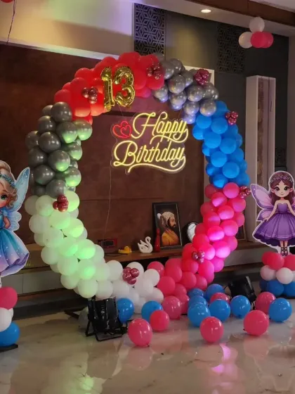 A fairy-themed 13th birthday with a multi-colored balloon ring and fairy cutouts.