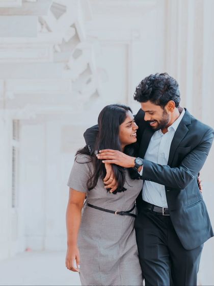 A candid walking shot in a bright, airy corridor, capturing the couple in a moment of shared happiness.