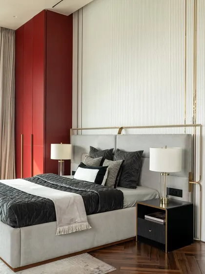 The master bedroom in our 2,700 sq.ft. apartment project features a bold maroon wardrobe that contrasts beautifully with the neutral tones of the bed and walls. Brass details and fluted textures add a layer of subtle glamour and sophistication.