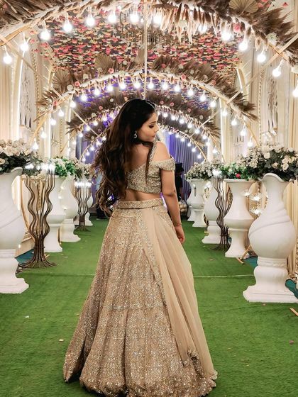 A back view of the client in the same lehenga, set against a beautiful floral archway.