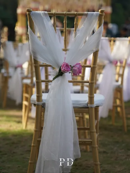 An elegant detail on the guest chairs, with white tulle and fresh pink roses, adding a touch of romance to the ceremony seating.