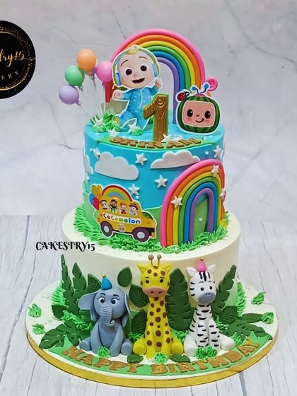A fun two-tier cake that merges the worlds of Cocomelon and the jungle. The top tier features JJ and a rainbow, while the bottom has adorable fondant jungle animals.