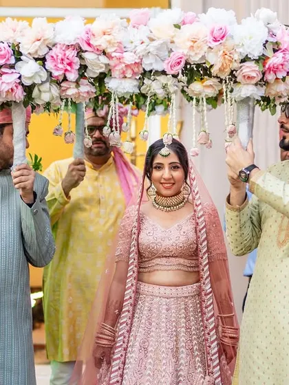A beautiful bridal entry under a phoolon ki chadar. The bride's happy expression and the elegant floral arrangement make this a picture-perfect moment.
