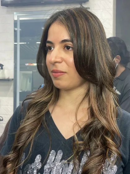 A close-up of a client's new hairstyle, featuring soft curls and subtle highlights. This look is perfect for adding texture and dimension to medium-length hair.