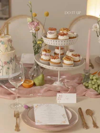 A view of the dessert spread at a romantic anniversary brunch. The tiered stand with floral cupcakes, the custom cake, and the elegant place setting all contribute to a cohesive and beautiful design.