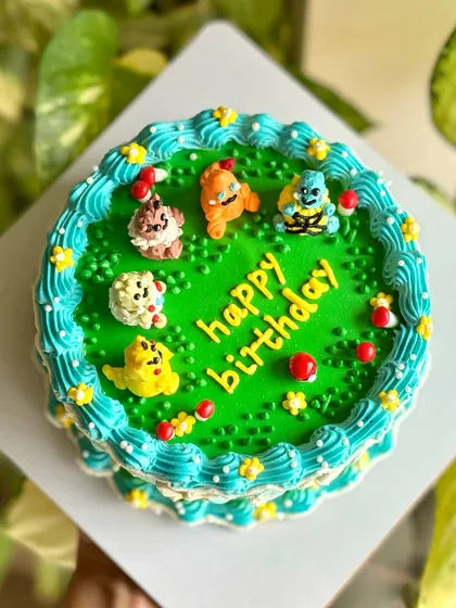 Pokémon dream cake alert! This custom cake features edible Pokémon characters like Pikachu and Charmander crafted with buttercream, sitting on a vibrant green field.