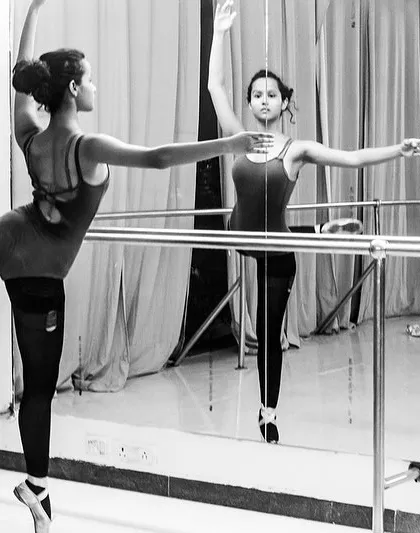 A ballerina at the barre, reflected in the mirror. This black and white photo captures the discipline and grace of a dancer.