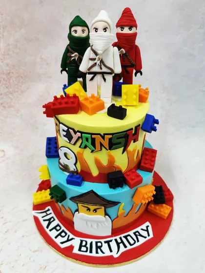 Action and color collide in this dynamic two-tier Ninjago cake. Featuring multiple ninja figurines amidst a flurry of edible Lego blocks and flame details, this creation demonstrates our ability to build exciting, story-driven cakes for fans of the series.