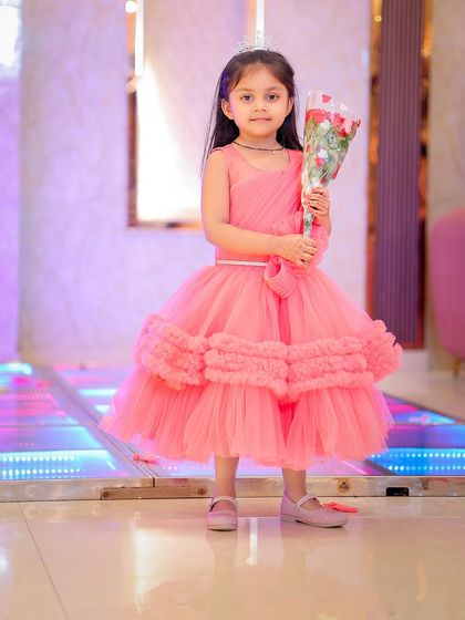 A full-length shot of the birthday girl holding a bouquet of flowers. The lit-up floor and decor add a dynamic feel to the photograph.