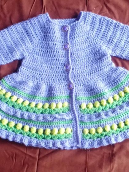 A variation of our textured baby cardigan, this one in light purple with soft yellow and green accents. The gentle color palette makes it a sweet and charming choice.