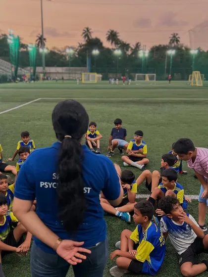 A female sports psychologist leads a session with a group of young players at dusk. This image shows that learning about the mental side of the game is an integral part of our training.