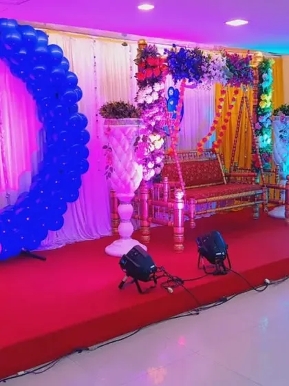 A baby shower stage combining multiple elements. This setup includes a balloon moon arch, a traditional floral jhula, and an illuminated seating moon, offering various beautiful spots for photos.
