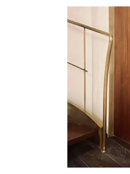 A detail of the spiral staircase, showing how the aged brass handrail curves and terminates at the floor. It is deeply satisfying when a design is resolved so purely.