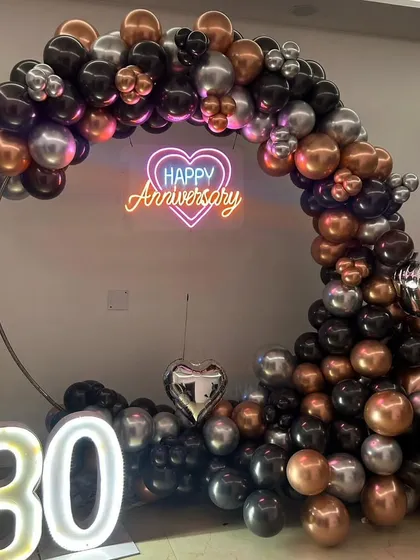 Here is a stylish and modern decoration I did for a 30th anniversary. The setup uses a sophisticated color palette of black, bronze, and silver balloons, with a heart-shaped neon sign and a large light-up number "30".