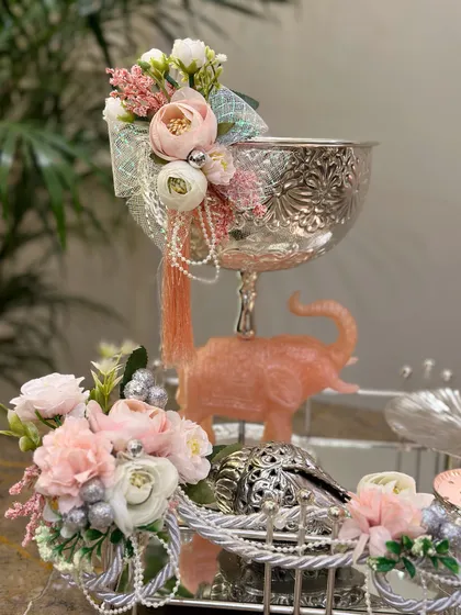 A closer look at the intricate details of our pink and silver Diwali hamper. The engraved silver bowl and delicate floral arrangements make this a truly special gift for your loved ones.