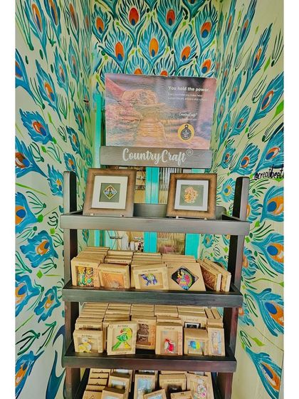 A look at one of our retail corners against a vibrant peacock mural. My café is a great place to discover and support small, local craft businesses.