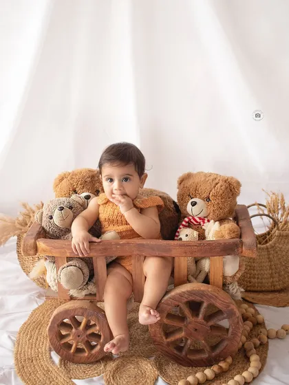 A baby boy in a rustic wooden cart with his teddy bears. This simple, prop-focused shot has a timeless, nostalgic feel.