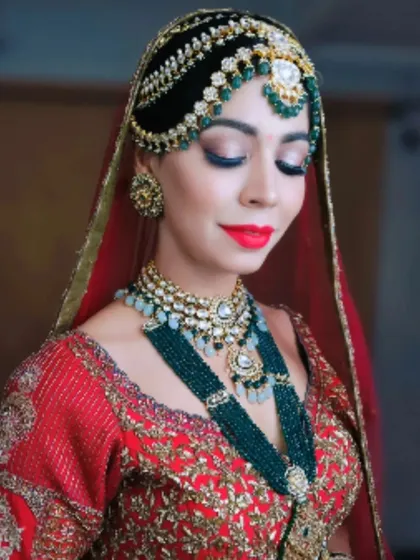 A close-up of a luxurious bridal look. The hair is styled into an elaborate structure that supports a heavy, traditional matha patti, demonstrating how to balance intricate hair artistry with opulent bridal accessories.