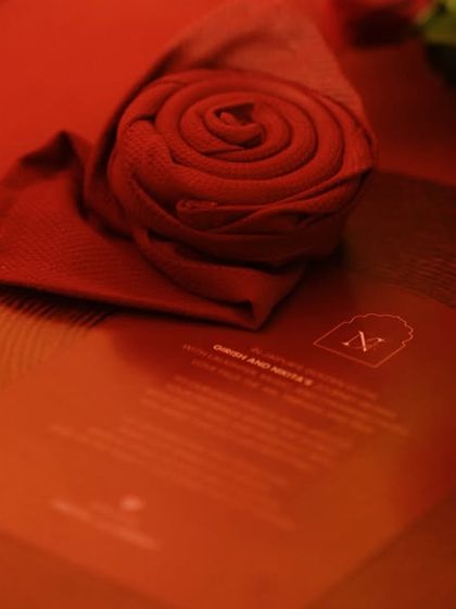 A close-up of the place setting, featuring a custom menu and a napkin elegantly folded into a rose, sitting atop a rustic wooden charger plate.