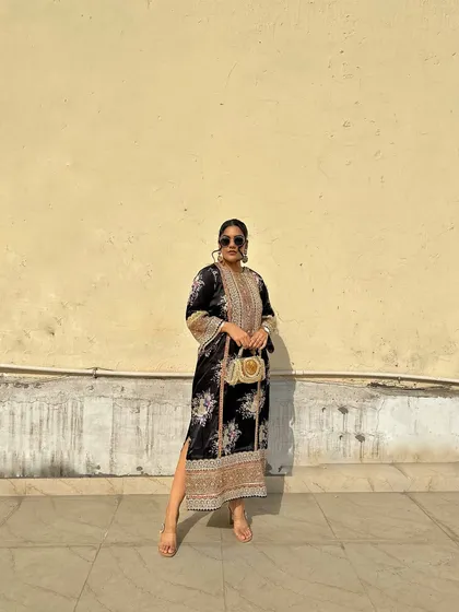 This full-length shot shows how the light-colored woven clutch brightens up the dark floral kurta, making it suitable for both day and evening events.