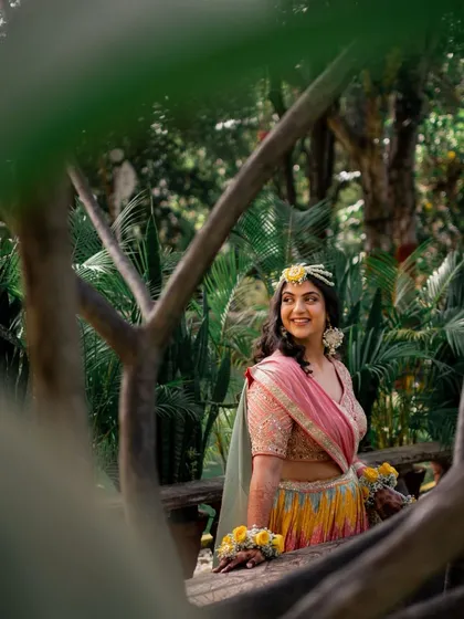 A beautiful candid of Vibhuti at her Haldi ceremony, surrounded by lush greenery. Her makeup is natural and enhances her happy glow.