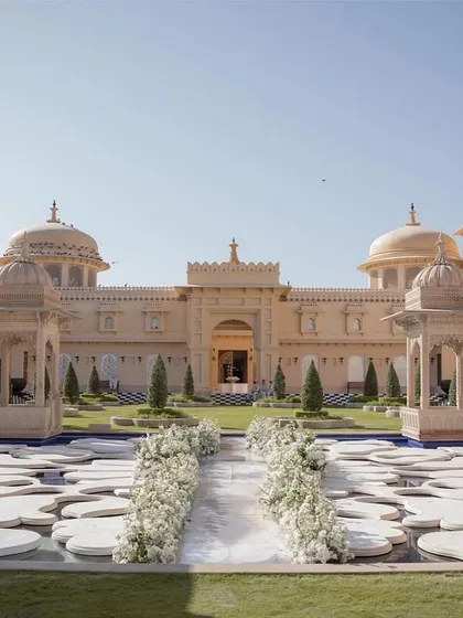 A breathtaking Anand Karaj ceremony at The Oberoi Udaivilas. The aisle, lined with pristine white florals, leads to a serene water body, perfectly framing the majestic palace architecture for this destination wedding in Udaipur.