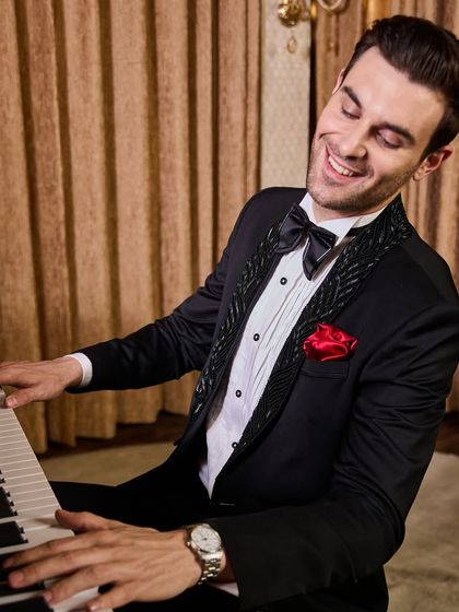 A joyful expression captures the feeling of wearing a perfectly tailored outfit. This close-up highlights the detailed lapel, the classic bow tie, and the overall celebratory mood this tuxedo inspires.