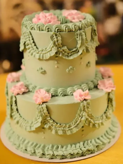A stunning two-tier vintage style cake for an engagement. I used a classic piping technique to create the intricate buttercream frills and added delicate pink flowers for a soft, romantic look. These Lambeth style cakes are very popular for elegant events.