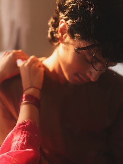 A close up on a simple gesture. The styling here is subtle, focusing on the texture of the fabrics and the connection between the models, enhanced by the warm lighting.
