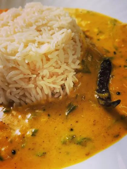 The rich and tangy Punjabi Kadhi enveloping a scoop of perfectly cooked basmati rice.