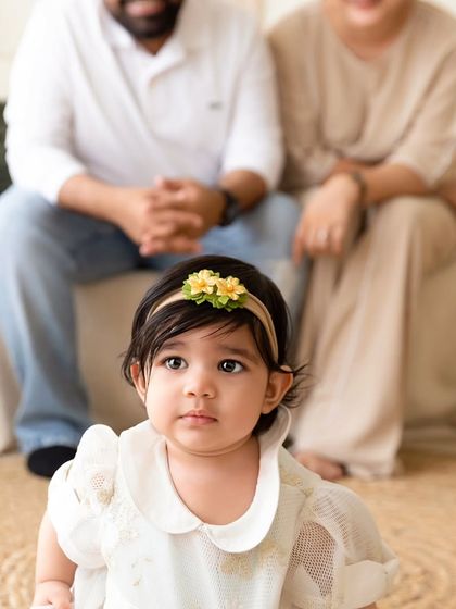 A creative family portrait with the baby in the foreground and her parents sitting softly out of focus behind her.