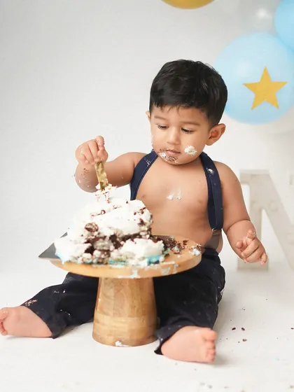 A little boy gets serious about his cake during his first birthday cake smash. The concentration on his face is priceless.