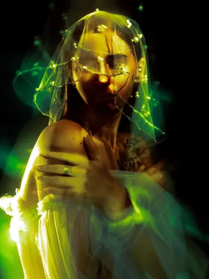An abstract portrait using light painting and long exposure. The green light trails obscure and illuminate the face, creating a mysterious and energetic image.