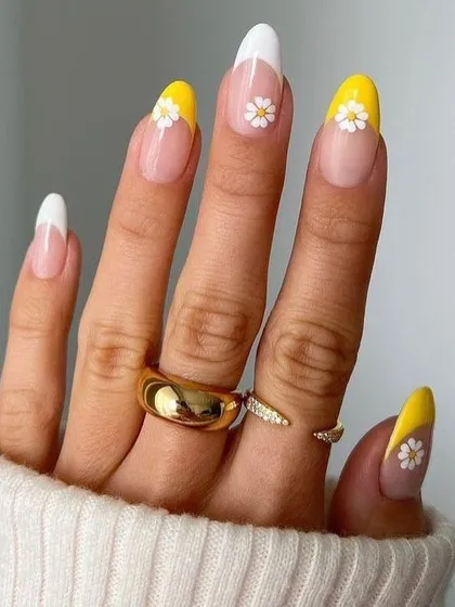 A cheerful and summery French manicure. This design features bright yellow tips on some nails and classic white tips on others, with adorable daisy art accents for a playful touch.