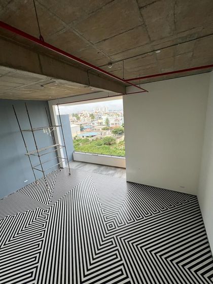 The social core of 'The Treehouse' apartments features a double-height lounge with a striking black and white geometric floor pattern. This space serves as a central hub, visually and functionally connecting different amenities and residential floors.