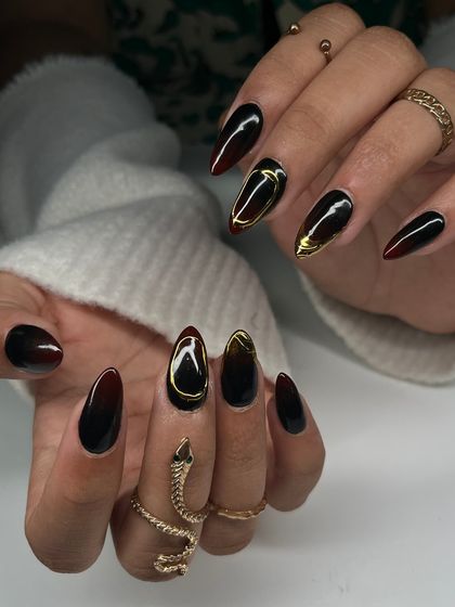 The full set of the dramatic black and red ombre nails. The combination of the dark gradient and the shiny gold chrome creates a look that is both edgy and luxurious.