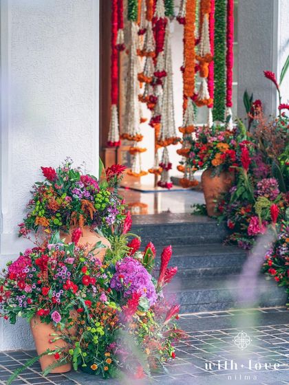The entrance to a home decorated for a Pellikuthuru ceremony, with vibrant floral arrangements and traditional garlands.