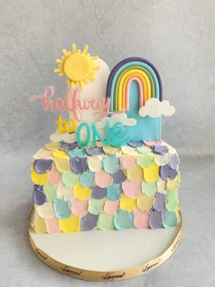 A colourful and happy cake to celebrate being "halfway to one." The pastel buttercream petals and rainbow topper are perfect for a six-month milestone.