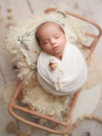 One month of pure wonder. This little one is peacefully asleep on a miniature sleigh prop, holding a tiny ballerina doll, creating a whimsical and sweet memory.