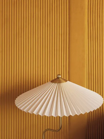 A pleated lampshade echoes the vertical, ribbed lines of the "Colonne" wallcovering behind it. This pairing highlights how our 3D designs can create a harmonious and serene, sculpted masterpiece.