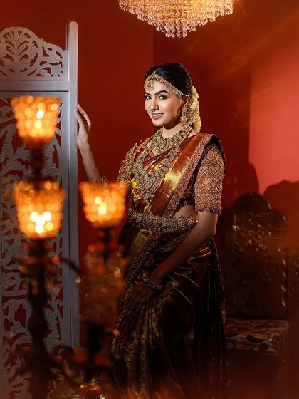 This shot uses our festive props, like the candle stands, to frame the model beautifully. The warm glow creates a magical atmosphere for this signature Muhurtham look.