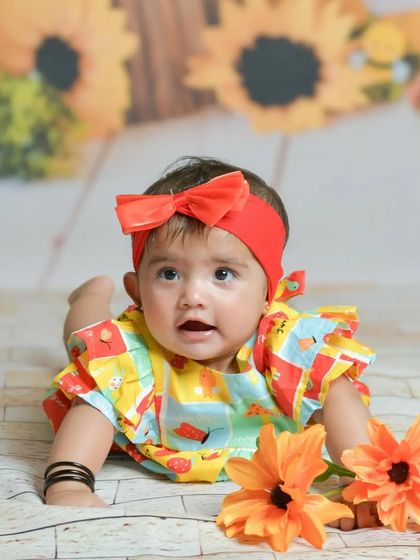 This older baby enjoys a colorful sunflower-themed setup. Her bright outfit and curious expression show how themed sessions can be adapted for babies at any milestone stage.