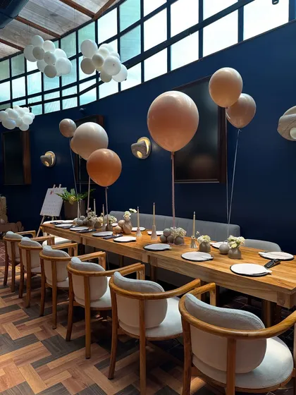 Floating balloons in soft, earthy tones add a touch of whimsy above the modern and elegant dining table at this neutral-themed baby shower.